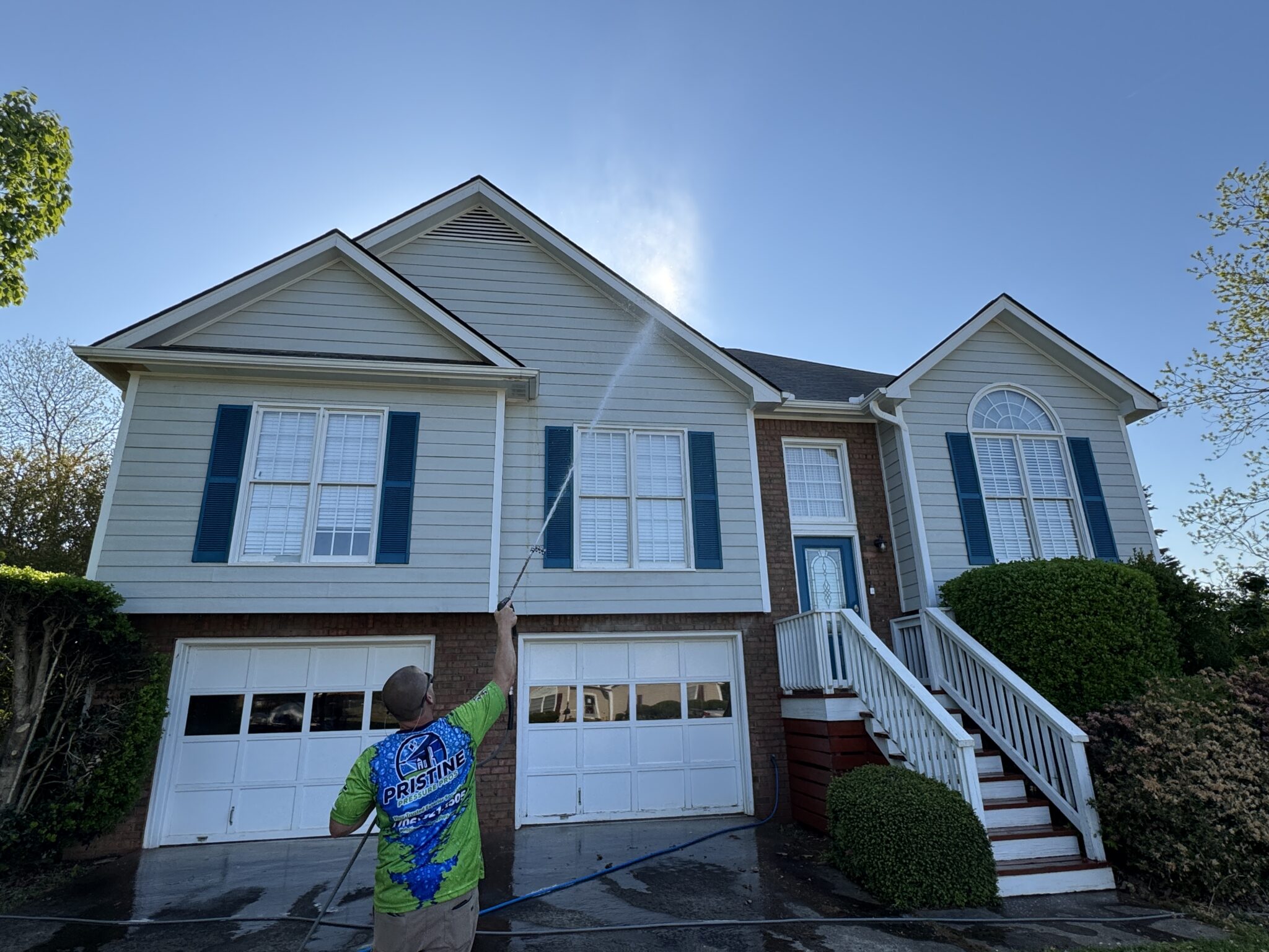 Pressure washing cleaning exterior surfaces of a residential property
